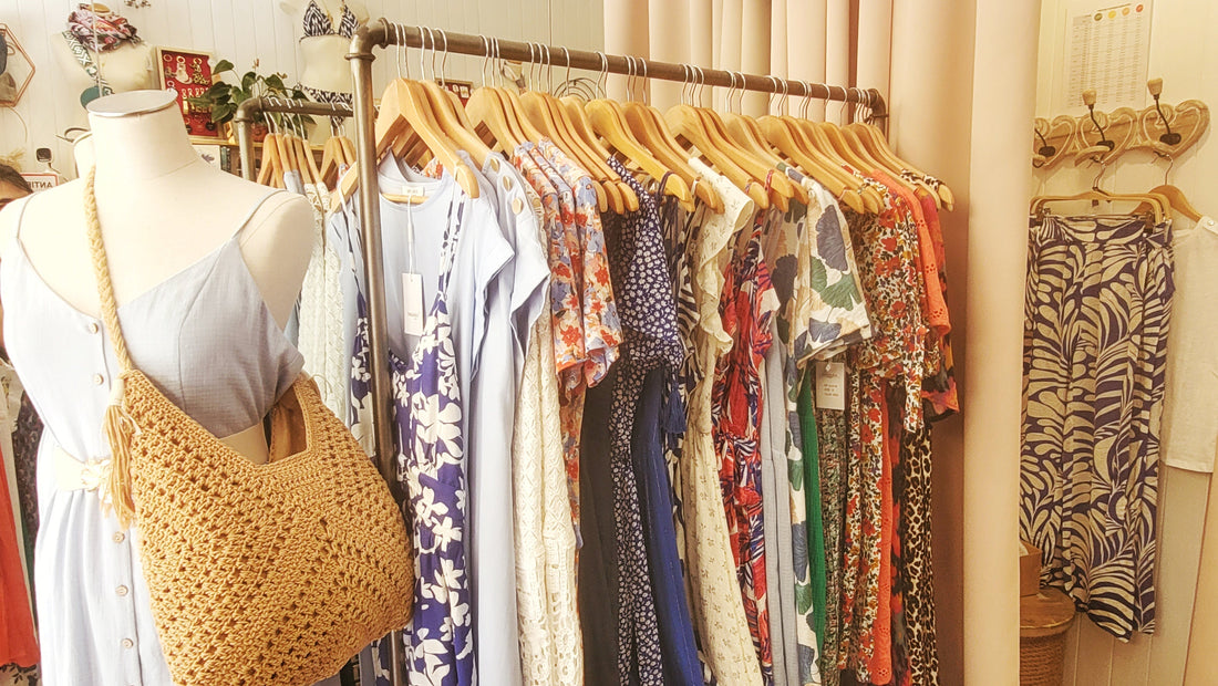 Intérieur d'une boutique féminine à l'ambiance douce, avec meubles en bois clair et murs rose poudré.