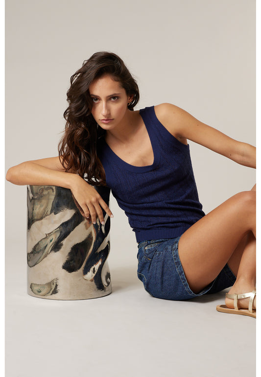 Débardeur navy KISHI en maille pointelle ajourée porté avec un short, look d’été féminin en pose assise de Deeluxe