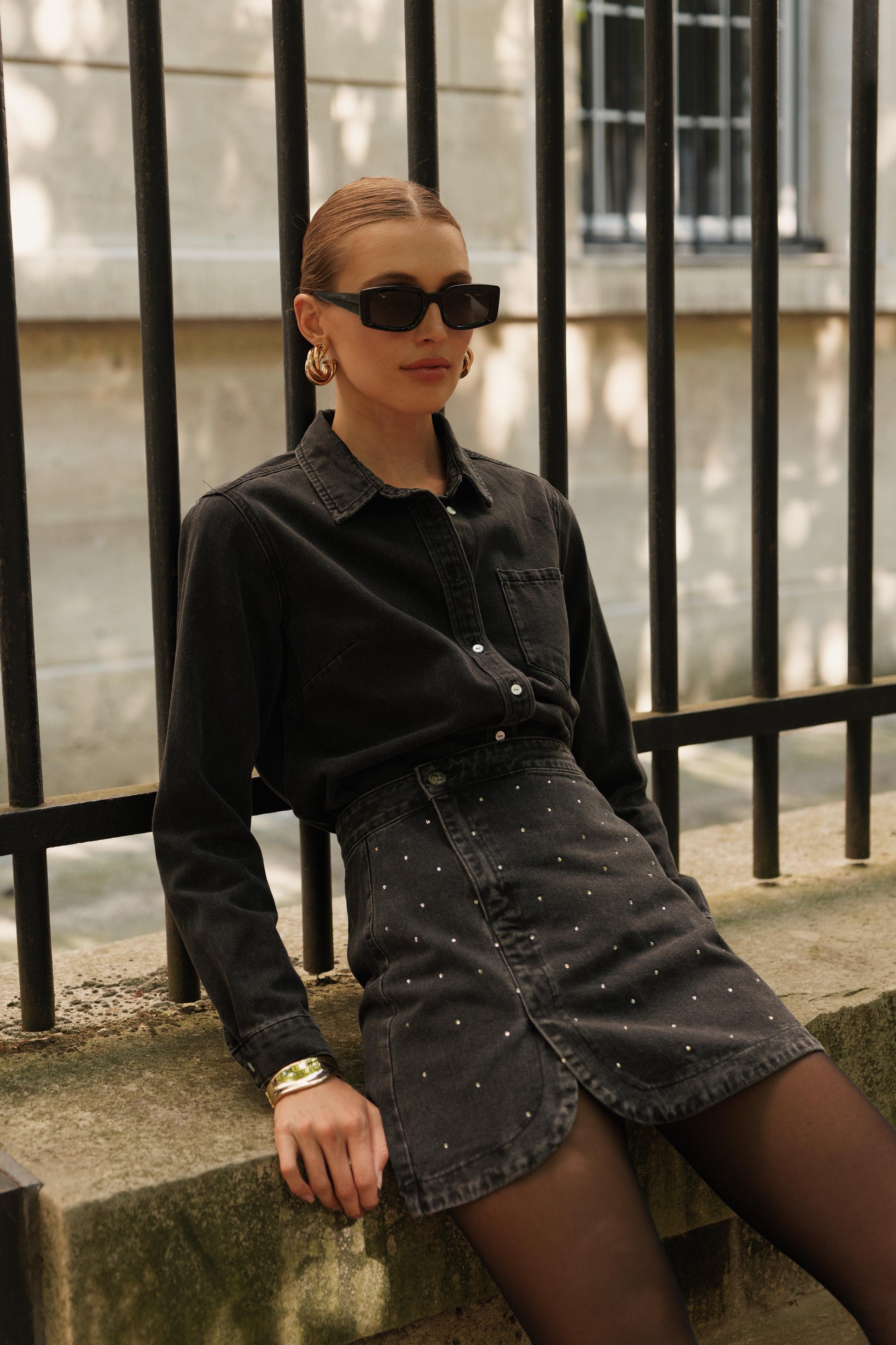 Jupe courte JUSTINE en denim noir délavé à strass, style rock chic, porté, allure moderne et facile de Oraije