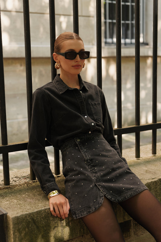 Jupe courte JUSTINE en denim noir délavé à strass, style rock chic, porté, allure moderne et facile de Oraije