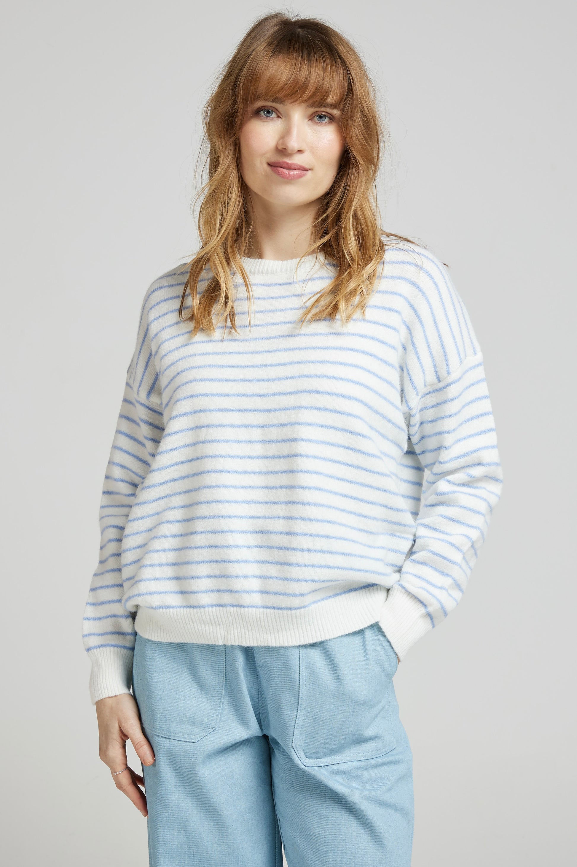 Pull crème à fines rayures ciel GAUTHIER porté par une femme, coupe droite et épaules tombantes, porté avec un pantalon bleu clair de Andy&Lucy