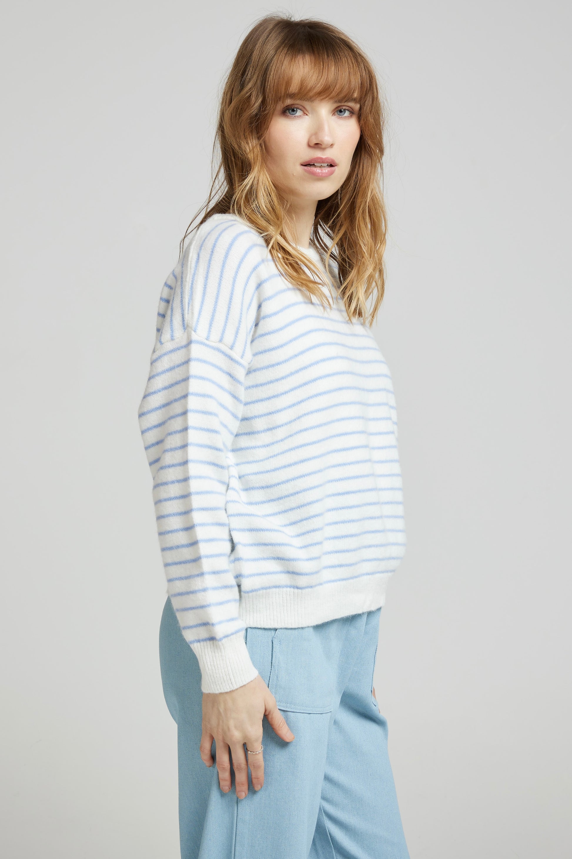 Pull GAUTHIER, crème à rayures ciel vu de profil, manches longues et coupe confortable, porté avec un pantalon clair de Andy&Lucy