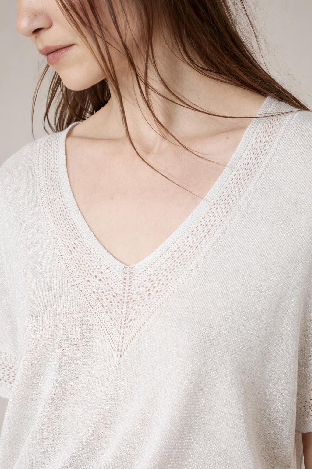 Zoom sur le détail crochet ajouré au col V du pull blanc irisé MARLYN, finition délicate qui remplace le bijou de Deeluxe
