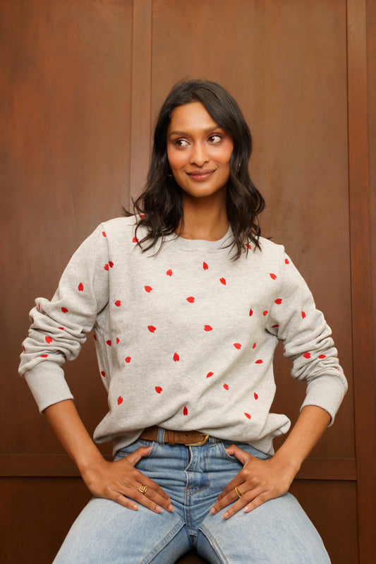 Sweat femme SW0041 gris chiné avec petits cœurs rouges brodés sur le devant et les manches, porté avec un jean de chez Jubylee
