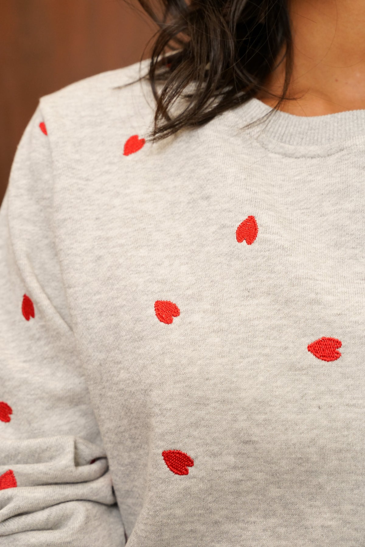 Gros plan sur les petits cœurs rouges brodés en relief du sweat femme SW0041 de Jubylle
